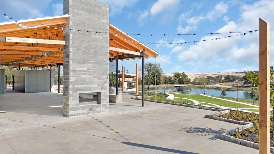 View of communal patio with a glass covered fireplace, a water view, and a pergola