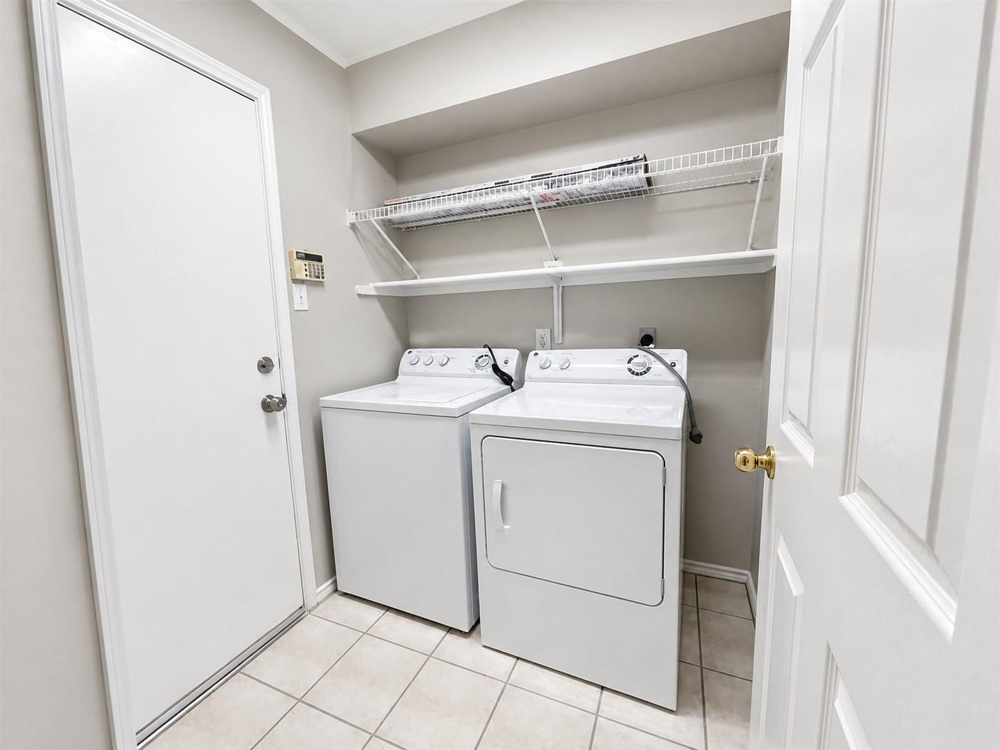 Laundry area featuring tile flooring, white walls, and a built-in wire shelving system