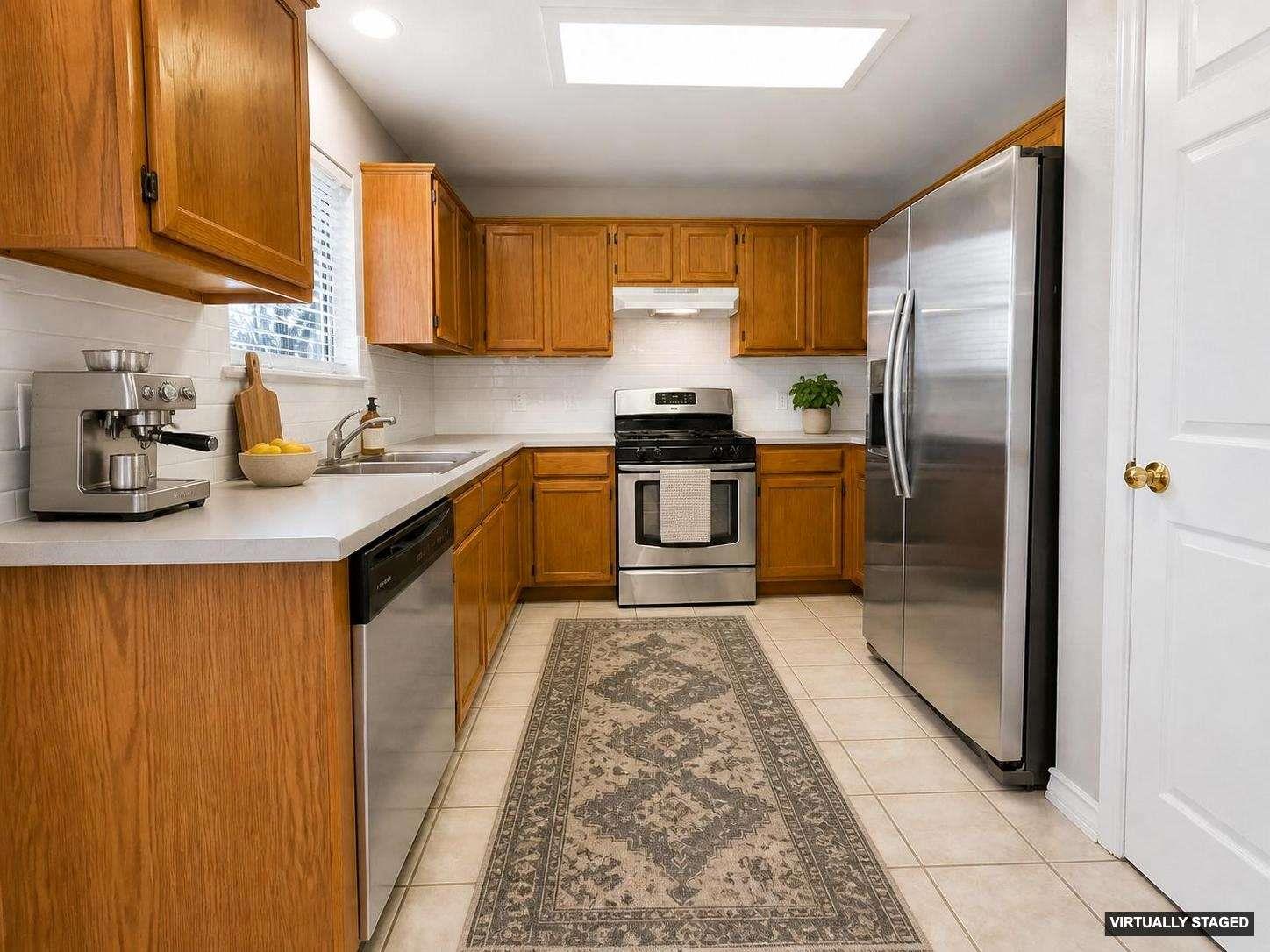 Kitchen featuring wood cabinetry, light-toned countertops, tile flooring, and stainless steel appliances including a refrigerator, dishwasher, and range