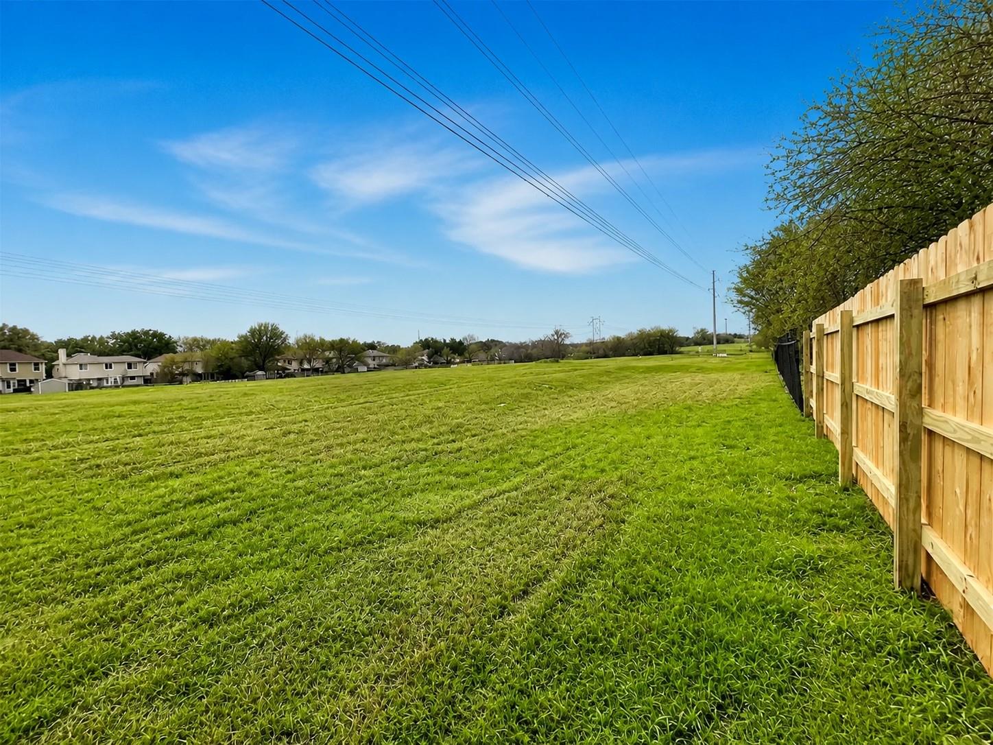 Expansive green field with a new wood privacy fence