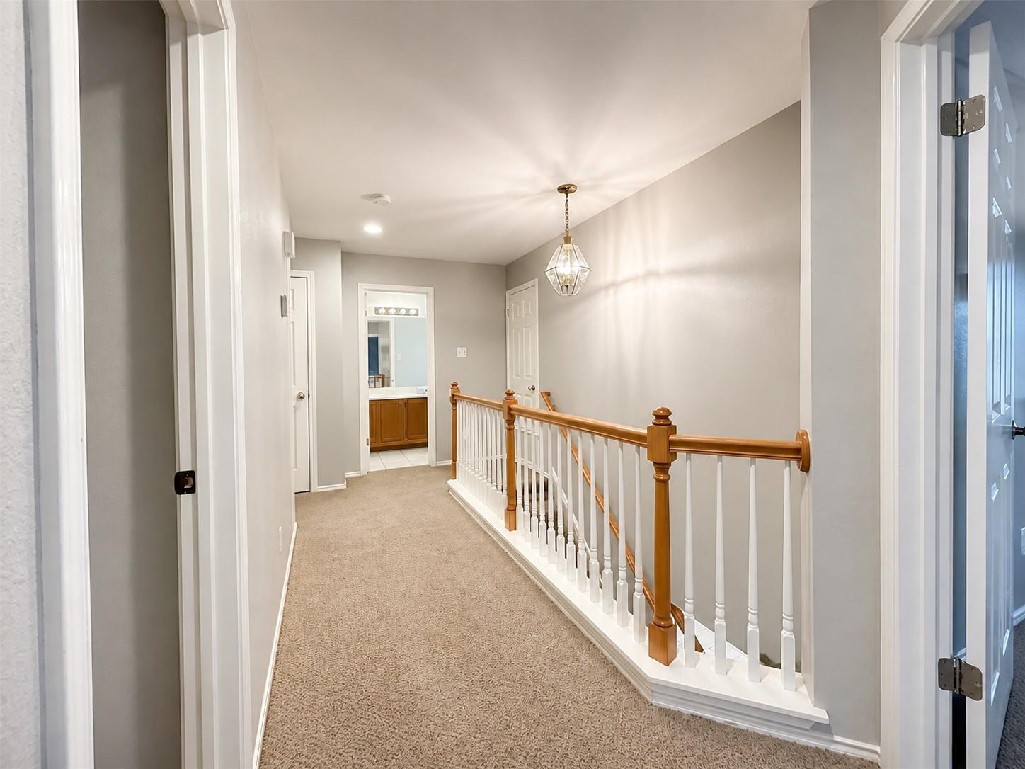 Upper-level hallway featuring a chandelier, recessed lighting, and carpeting