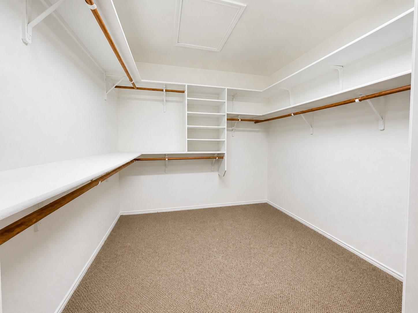 Walk-in closet featuring built-in shelving, multiple hanging rods, and broad storage surfaces