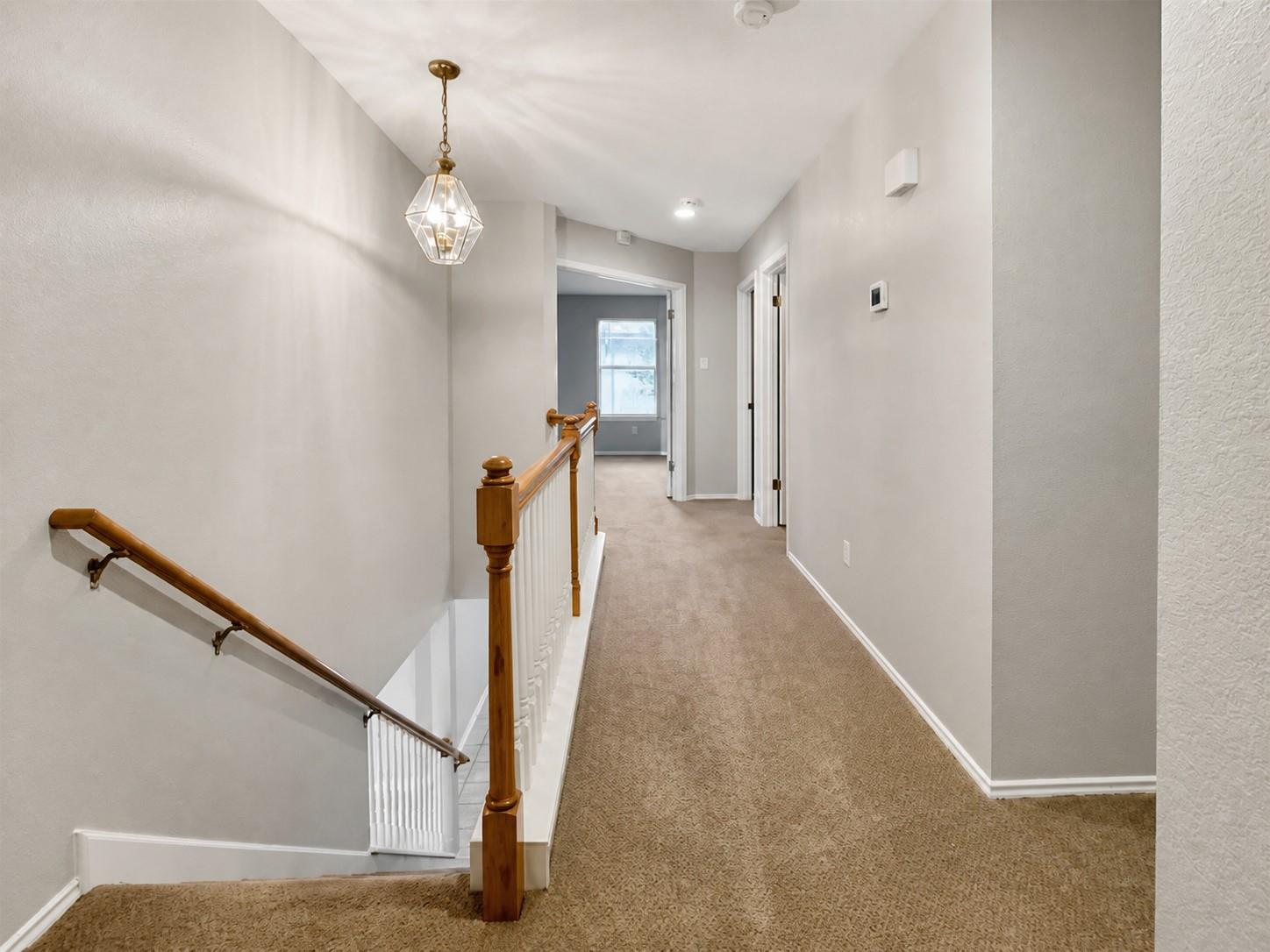Carpeted upper-level hallway with a wood handrail and white balusters