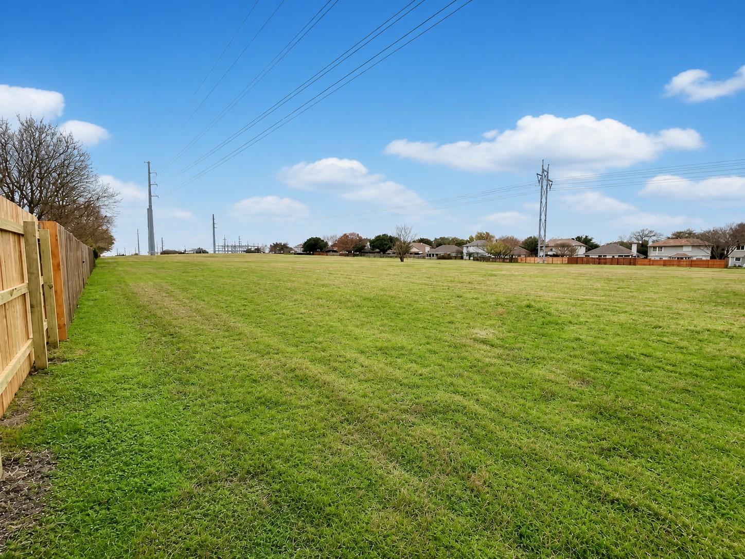 Expansive grassy lot bordered by a new wood privacy fence