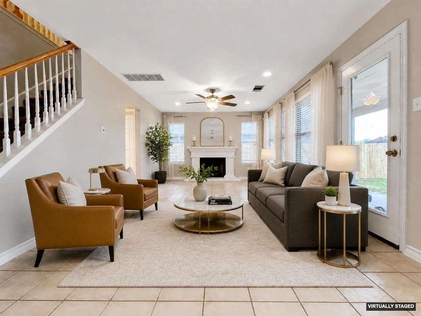 Open-concept living space featuring ceramic tile flooring, a fireplace with a mantel, multiple windows with blinds, and a staircase with wood railings