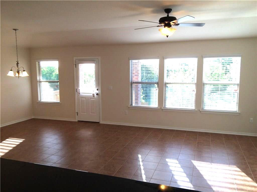 Natural light floods this versatile living area, complemented by sleek tile flooring and a ceiling fan for comfort.