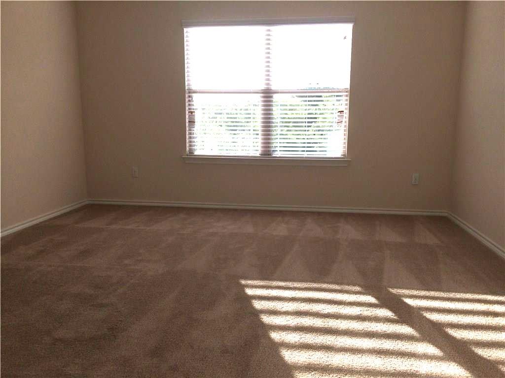 A spacious room offers comfortable carpeting, ready for personalization.