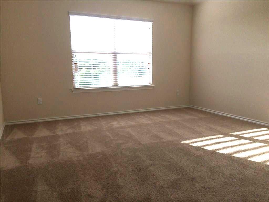 A spacious chamber with soft carpeting, naturally illuminated by a large window, provides a welcoming personal retreat.