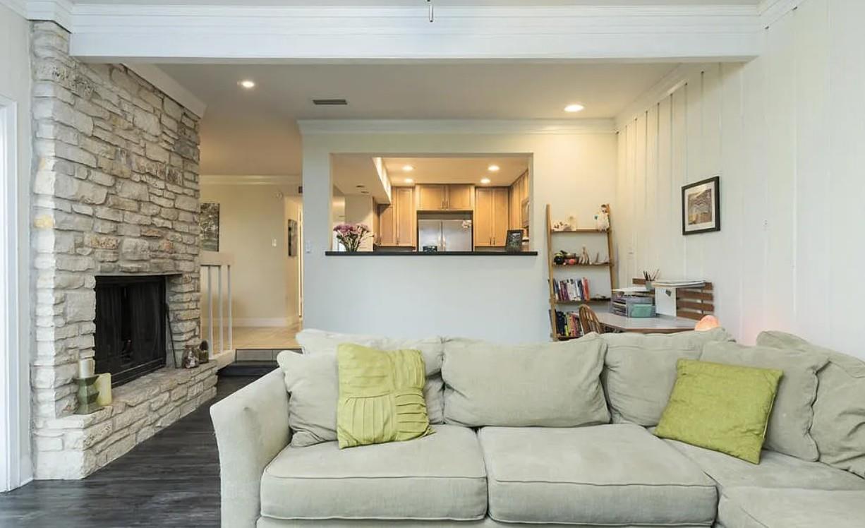 A cozy living space features a captivating stone fireplace and a pass-through window connecting to the kitchen.