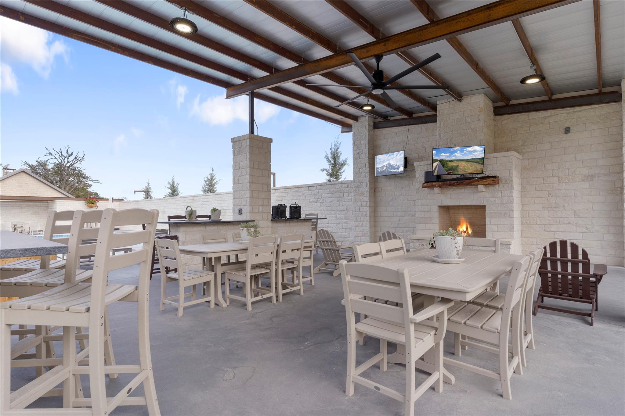 An inviting outdoor living space features a cozy fireplace and entertainment, perfect for gatherings.
