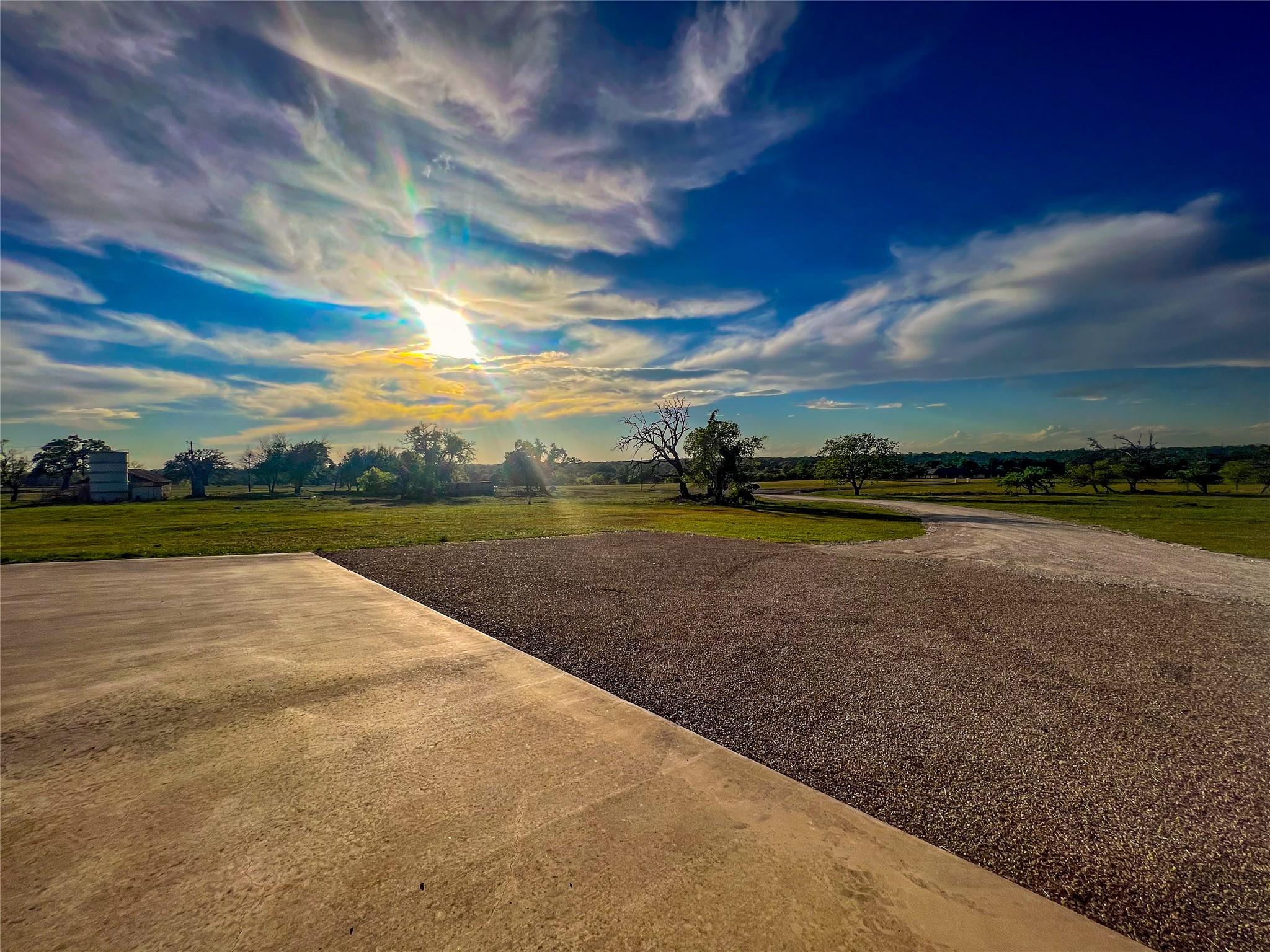 A tranquil rural landscape unfolds under a vibrant, sun-drenched sky.