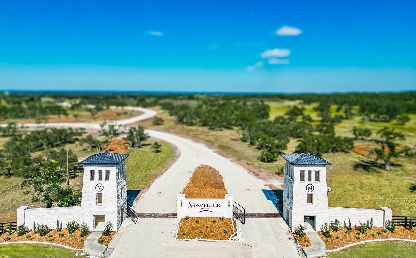 An inviting gated entrance features stone towers, leading to a long, winding private driveway.