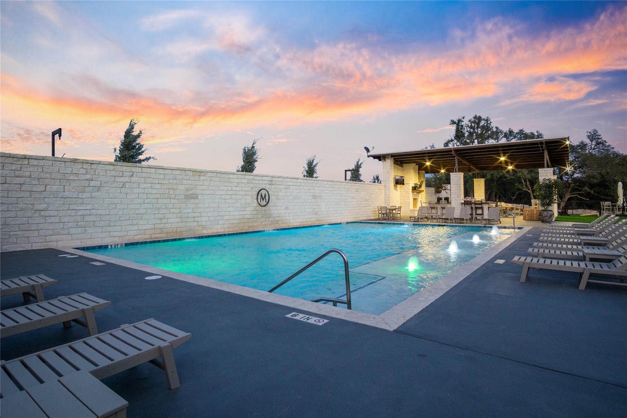 Pool at dusk featuring a patio area and a community pool