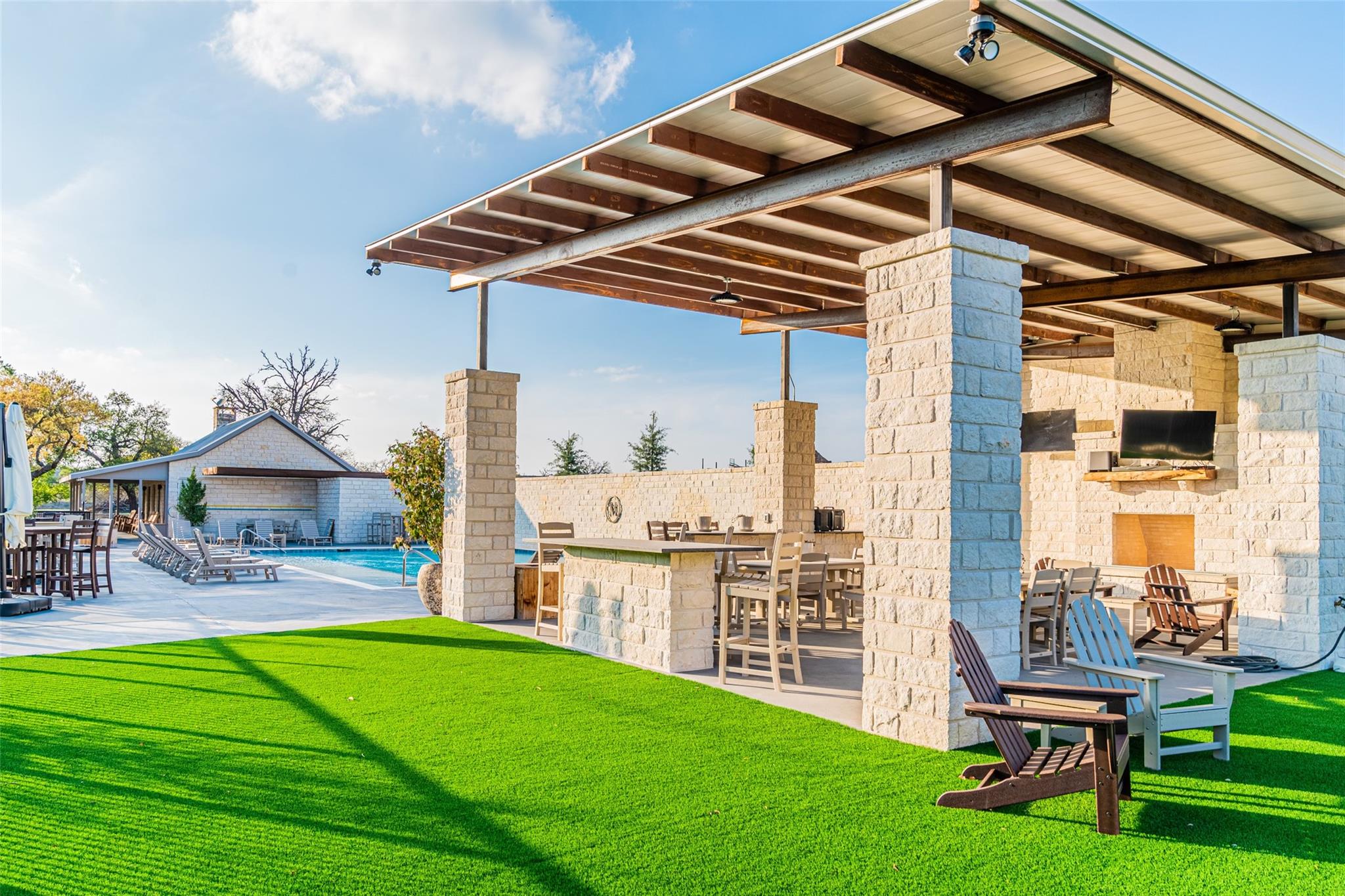 An inviting covered outdoor kitchen and lounge area complement a refreshing swimming pool, perfect for leisure.