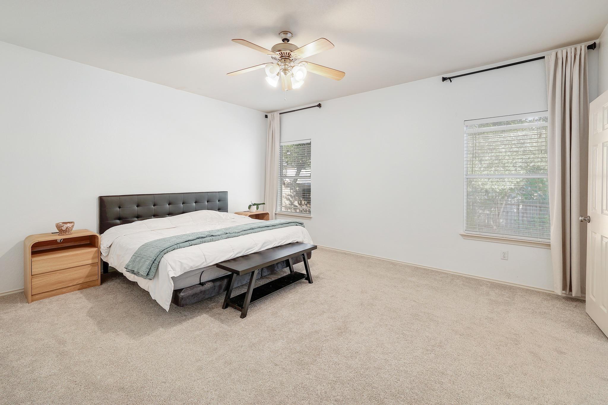 Plentiful natural light streams through multiple windows across this comfortable bedroom.