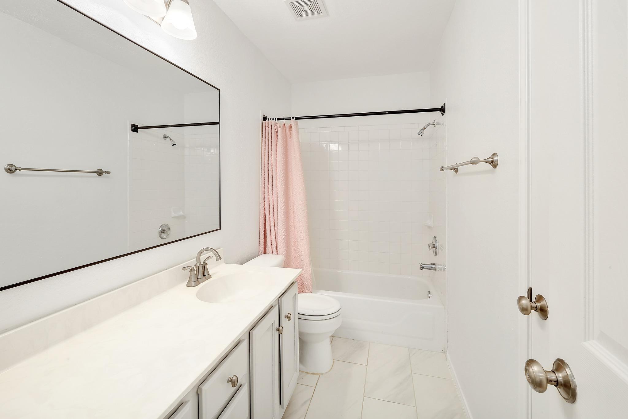 Gleaming tile floors and a classic vanity define this clean, functional bathroom.