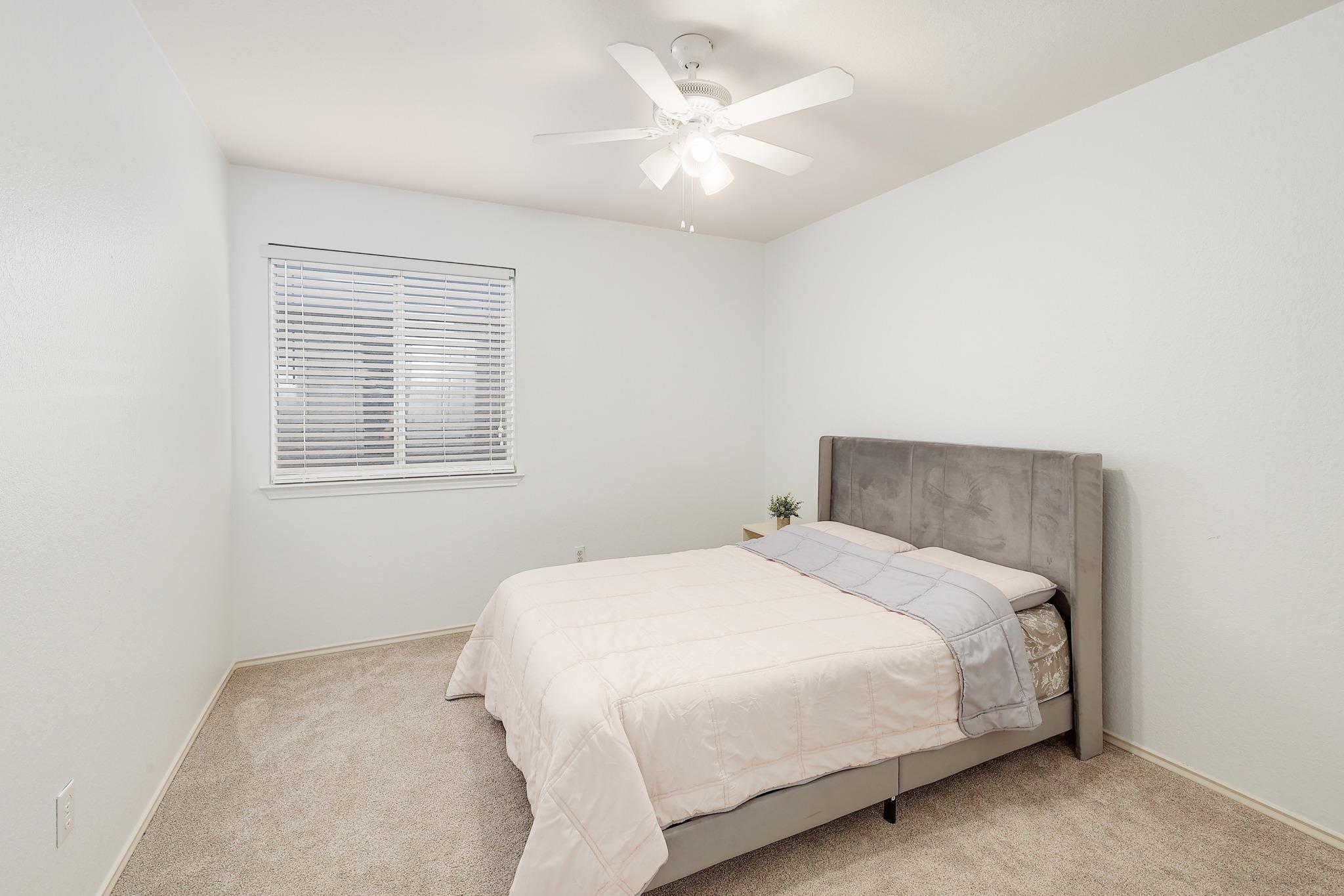 Soft carpeting underfoot and a wide window create a comfortable, inviting bedroom retreat.