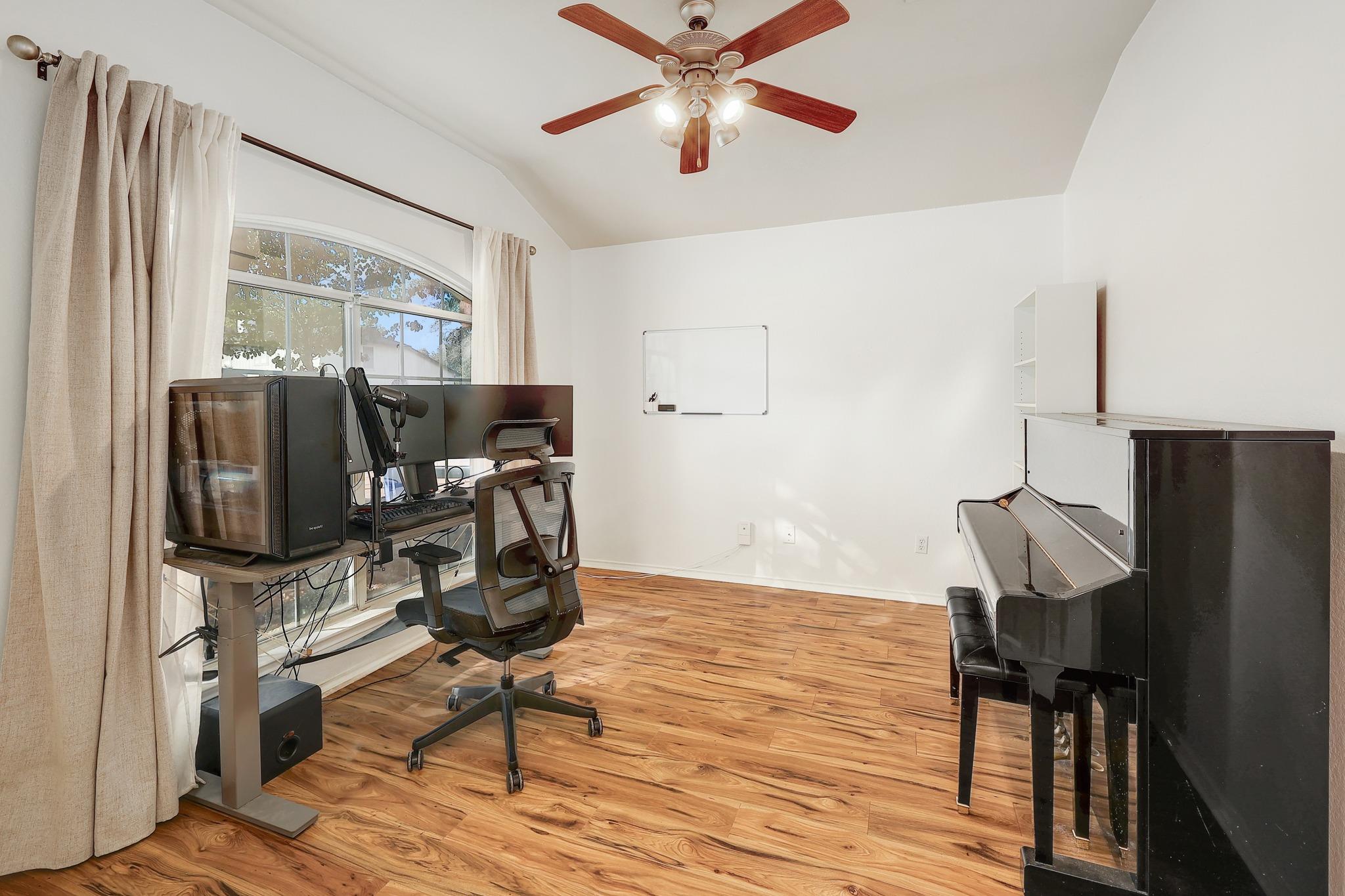 Rich wood-look flooring and a high vaulted ceiling define this versatile room.