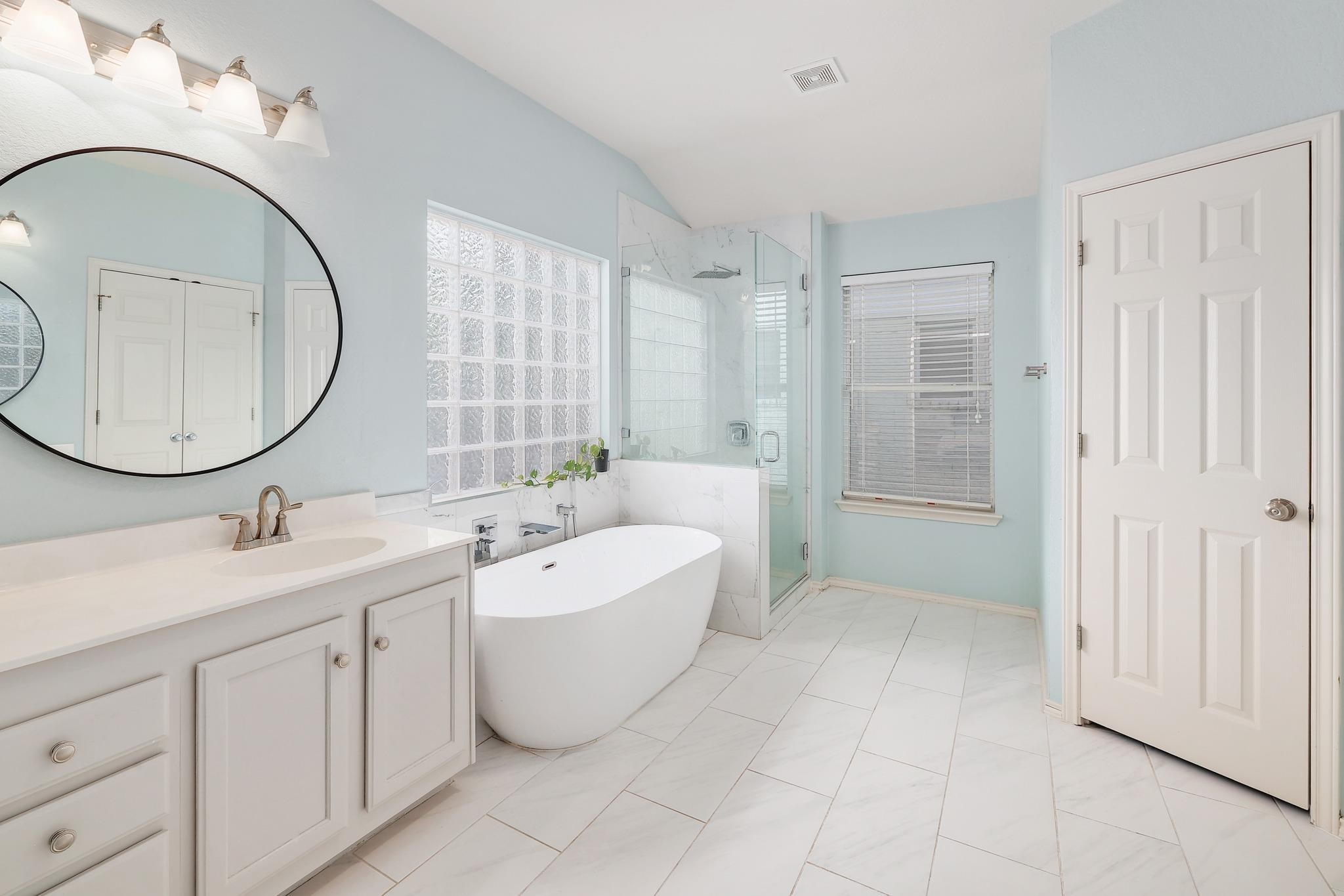 A modern soaking tub and glass shower highlight this tranquil, tile-floored bathroom.