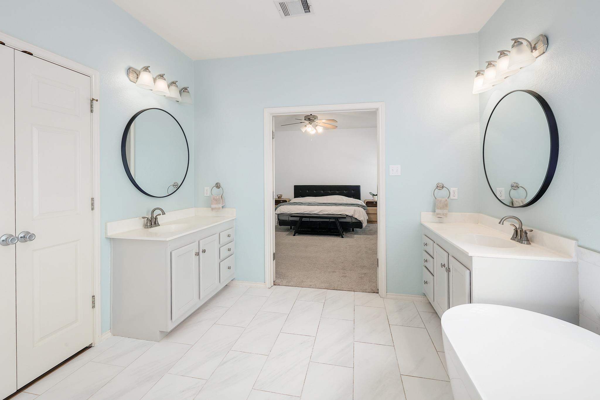 Double vanities with stone counters flank a spacious layout leading directly into the main suite.