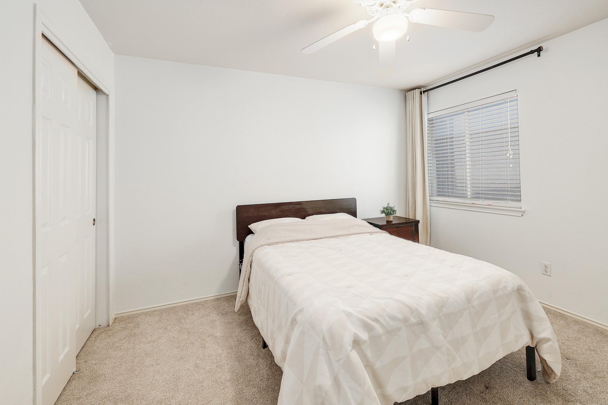 Plush carpeting and a large window create a comfortable, inviting atmosphere in this bedroom.