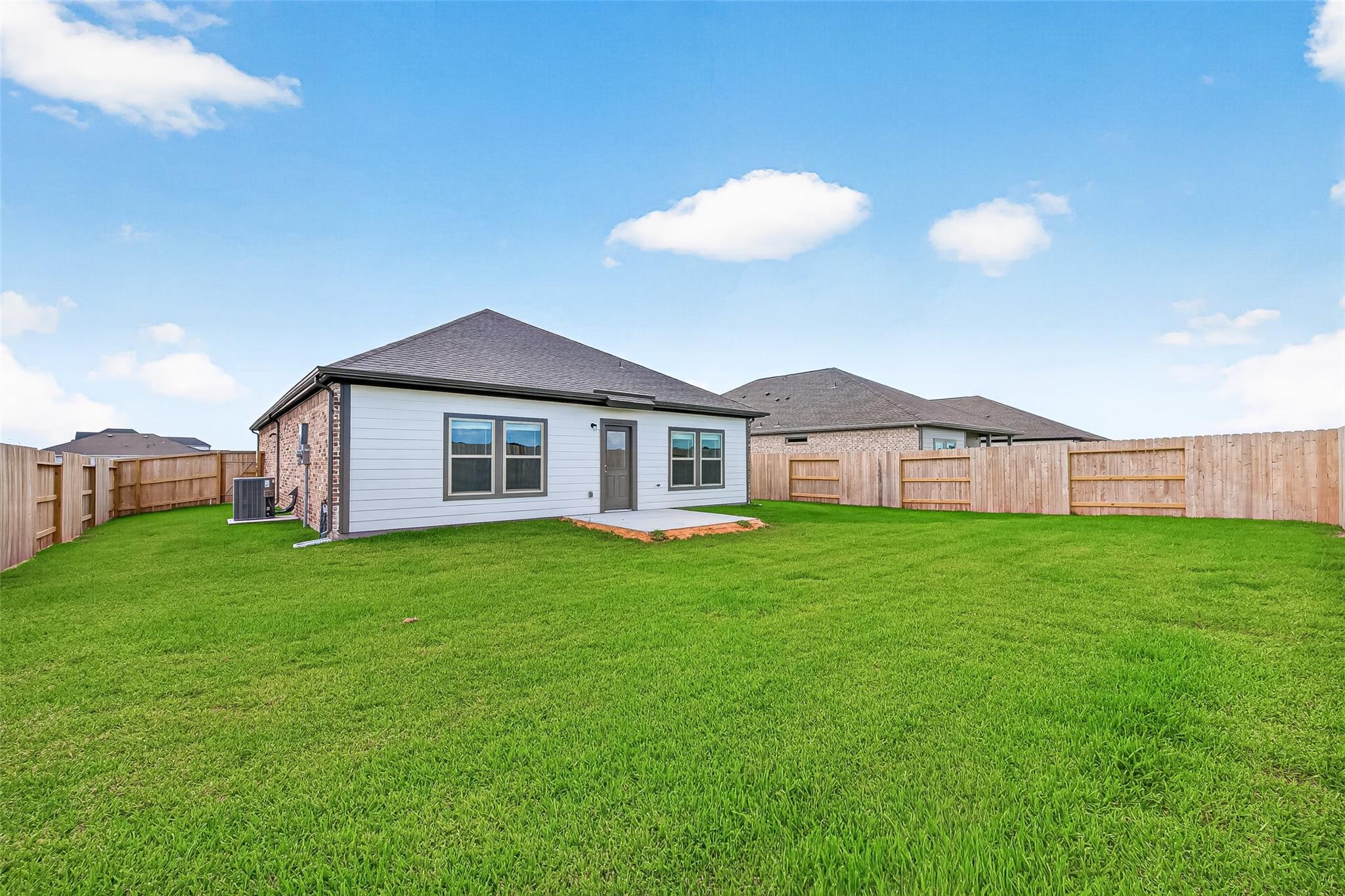 This photo showcases a single-story home with a modern exterior, featuring a spacious, well-maintained backyard enclosed by a wooden fence, perfect for outdoor activities and privacy.