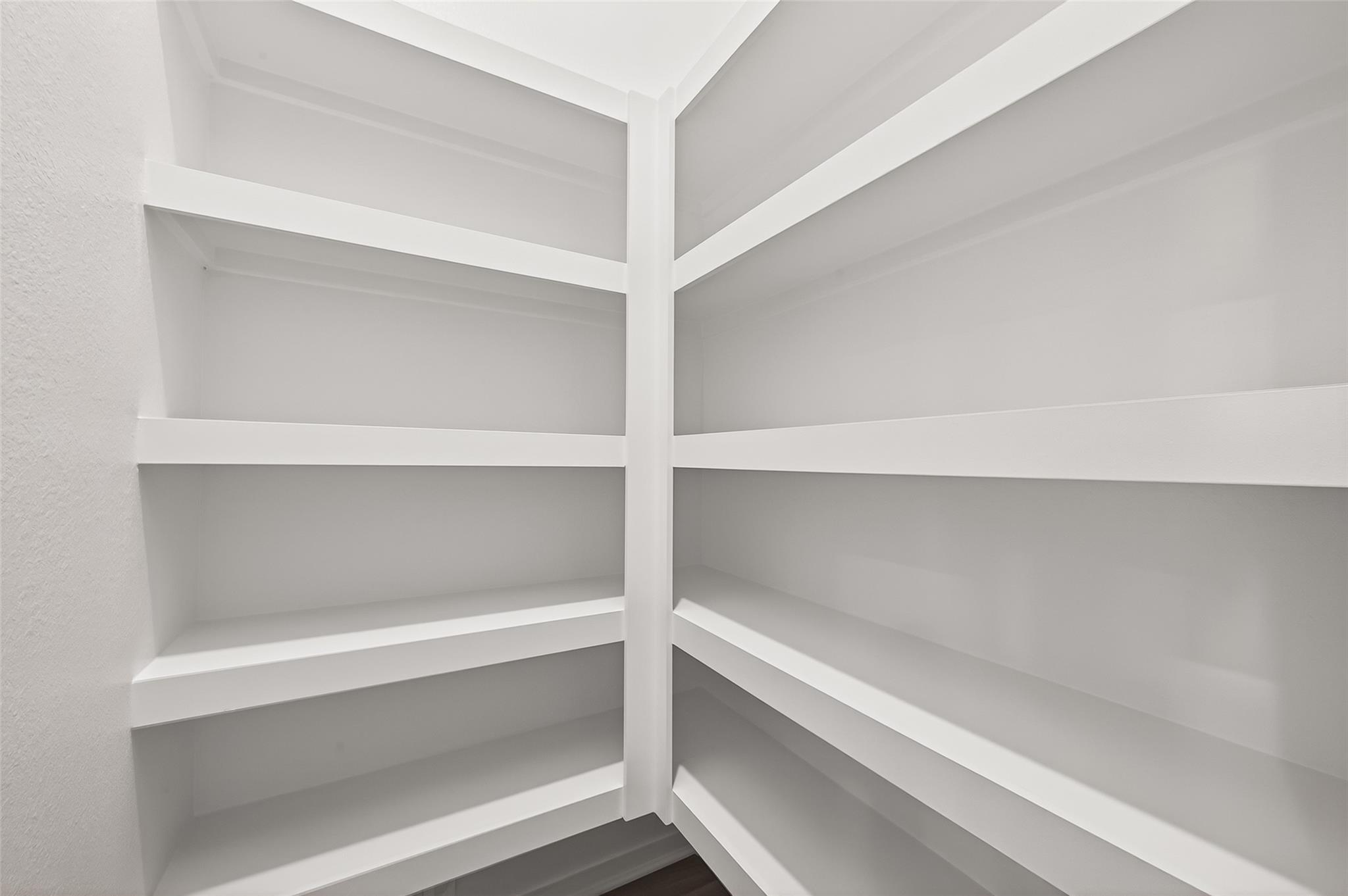This photo shows a spacious, well-lit pantry with white shelving, perfect for ample storage and organization.