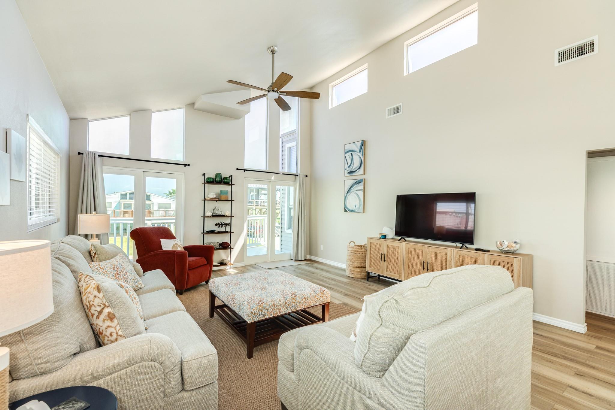 Living Room – Comfortable seating arrangement centered around a spacious layout, with easy access to the outdoor deck through double glass doors.