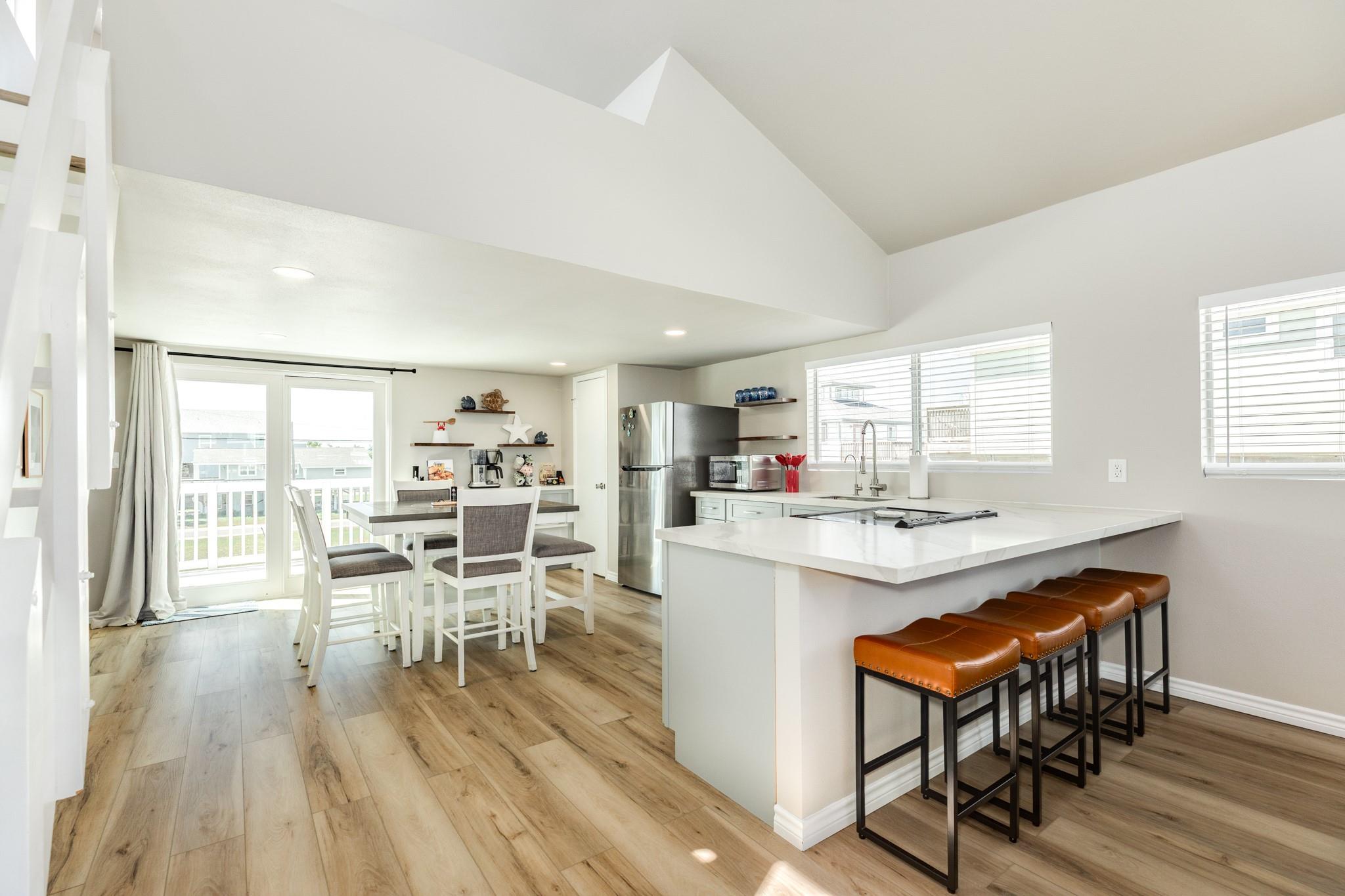 Kitchen & Breakfast Bar – Stylish kitchen featuring quartz countertops, soft-toned cabinetry, and a large breakfast bar with seating for casual dining.
