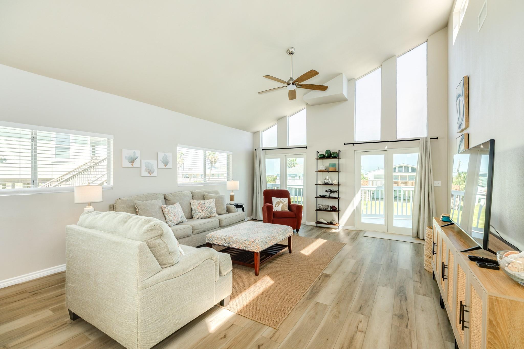 Living Room – Bright and inviting living area with soaring vaulted ceilings, expansive windows, and abundant natural light, creating an open and airy atmosphere.