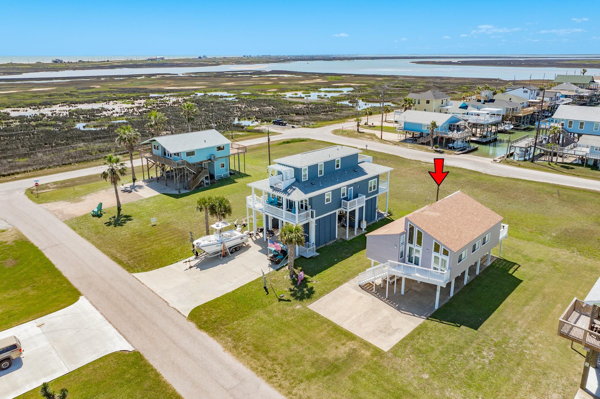 Aerial View – Positioned in a waterfront community, this property offers close proximity to canals and open water, ideal for boating and outdoor recreation. Neighboring homes and wide streets create an open, coastal setting.